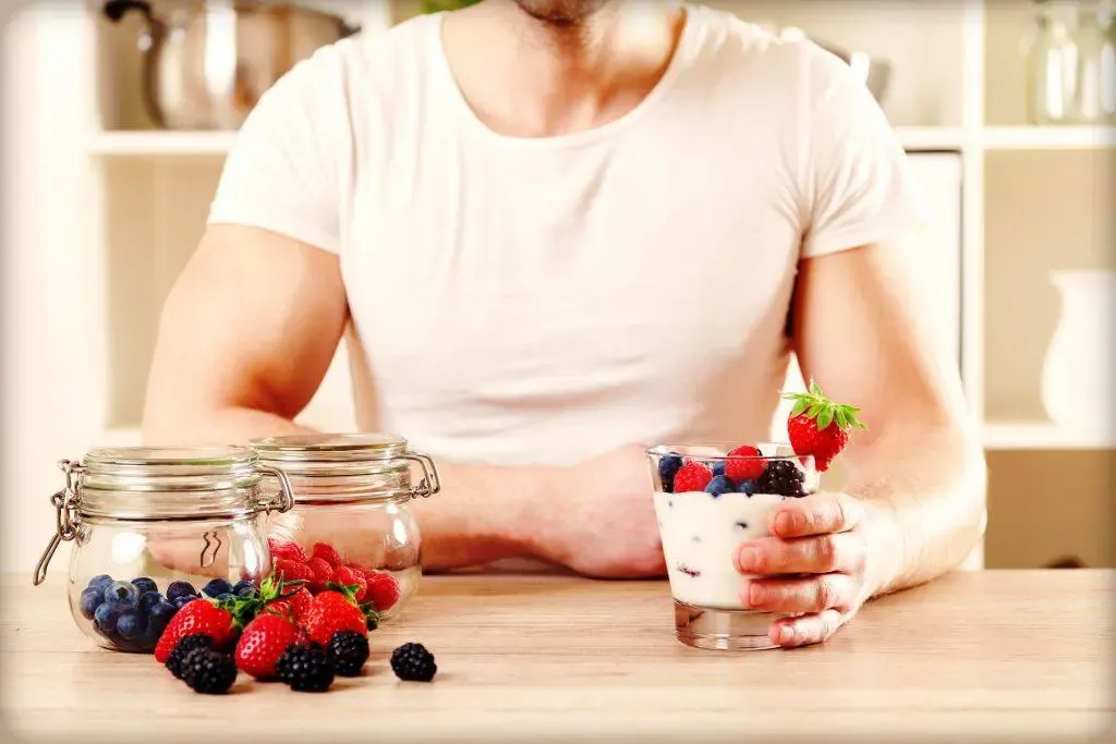 A man sitting at a table with a glass of yogurt, the best probiotic for men.