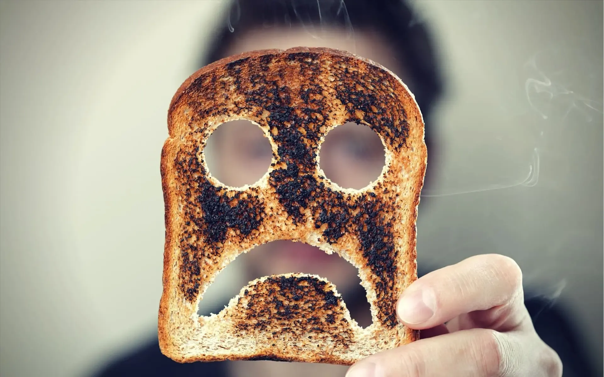 Natural MAO Inhibitors man holding up a burnt slice of toast with an unhappy smiley